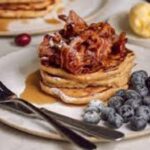 A colorful stack of pancakes with various toppings, served at Flat Iron Square in London