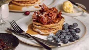 A colorful stack of pancakes with various toppings, served at Flat Iron Square in London