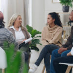 Image of a diverse group of women engaged in conversation about mental health and egg freezing, surrounded by social media icons, blogs, and support group materials.