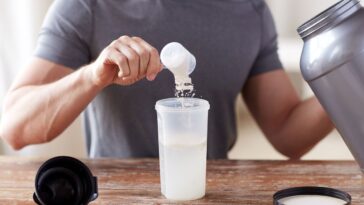 Illustration of a bodybuilder weighing himself on a scale, with creatine supplement containers and a water bottle nearby, symbolizing the effects of creatine on weight gain and muscle mass.