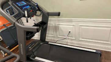 A person using a folding treadmill in a home gym, highlighting the compact design and space-saving feature of the treadmill in a modern living room.