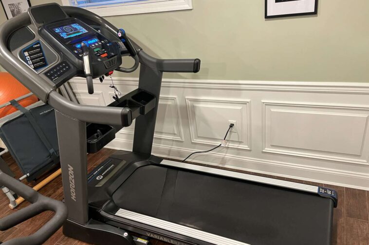 A person using a folding treadmill in a home gym, highlighting the compact design and space-saving feature of the treadmill in a modern living room.